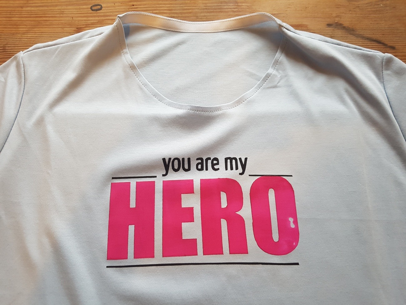 In pinken Buchstaben steht jetzt "HERO" auf dem T-Shirt