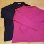 Der alte Pullover (schwarz) und der neue Pullover (pink) liegen leicht versetzt übereinander auf dem (Parkett-)boden