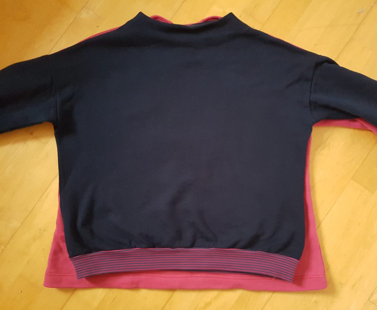 Schoppeffekt Der neue Pullover liegt über dem alten Pullover. Dabei sieht man, dass der neue Pullover deutlich kürzer geraten ist.