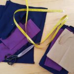 Die Zuschnittenen Sweatshirtteile, eine Stoffschere und ein Maßband