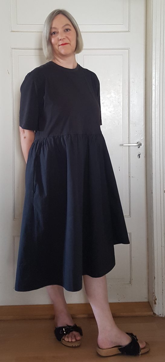 Sabine im Originalkleid vor einer weißen Tür.
