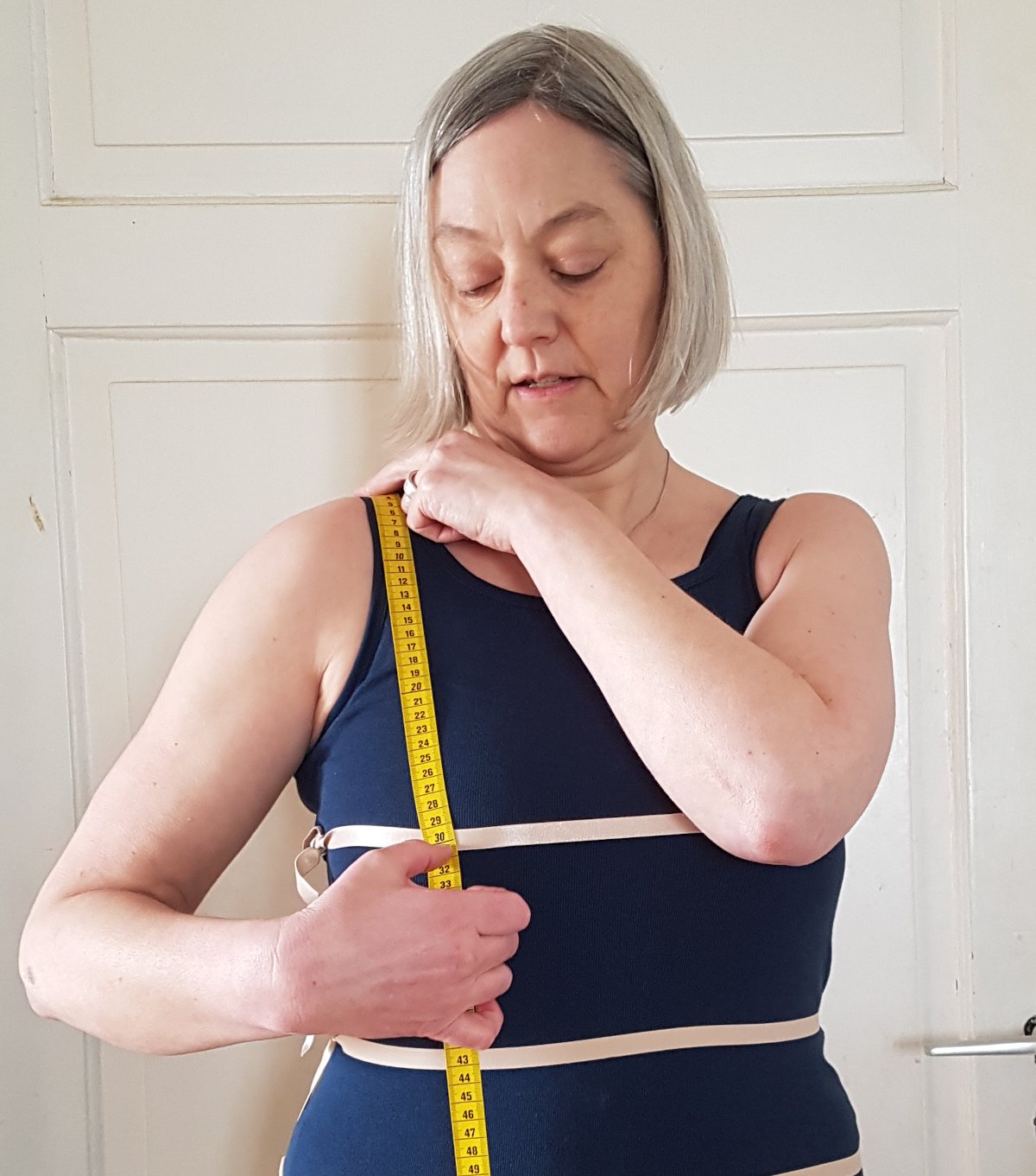 Brusttiefe messen Das Maßband verläuft von der Schulter zur Brustspitze. Sabine markiert mir dem Daumen, wo sie das Maß ablesen muss.