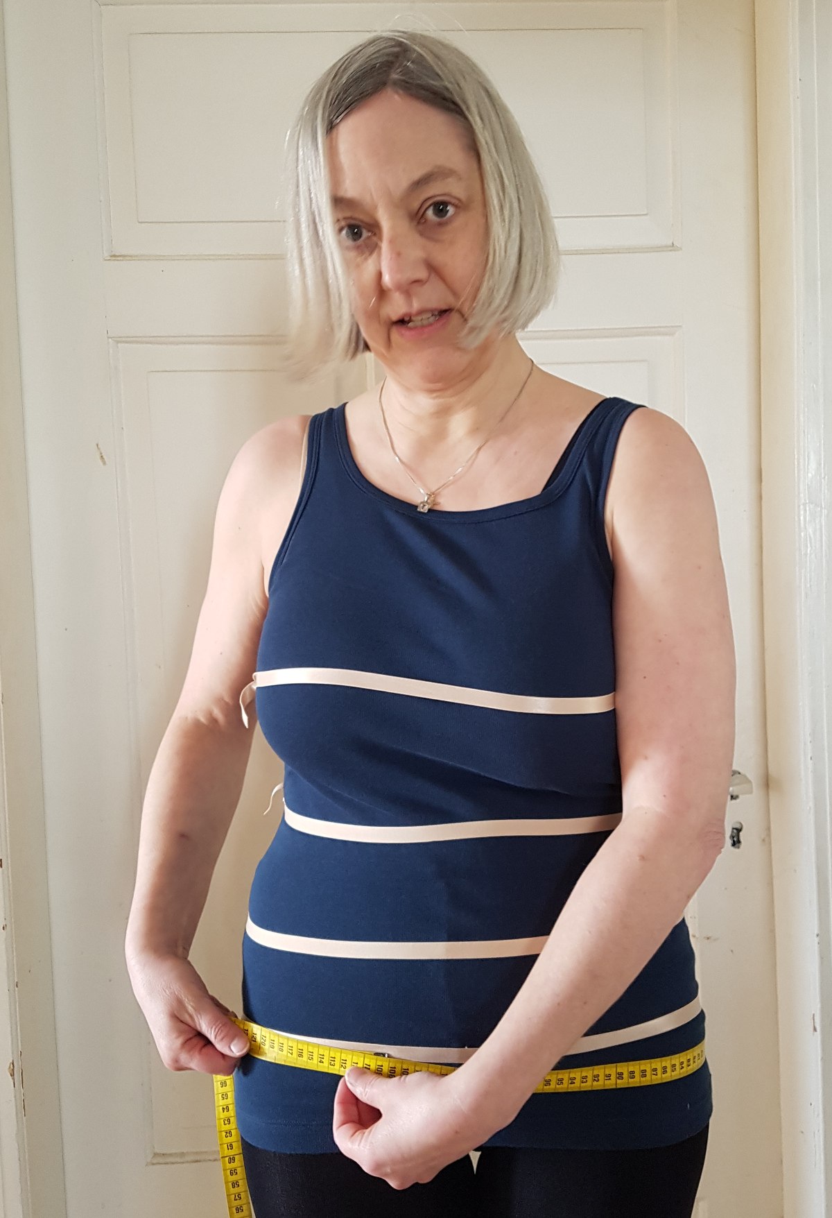 Hüftumfang messen Das Maßband liegt um die Hüfte. Sabine schaut in die Kamera, aber nicht besonders vorteilhaft.