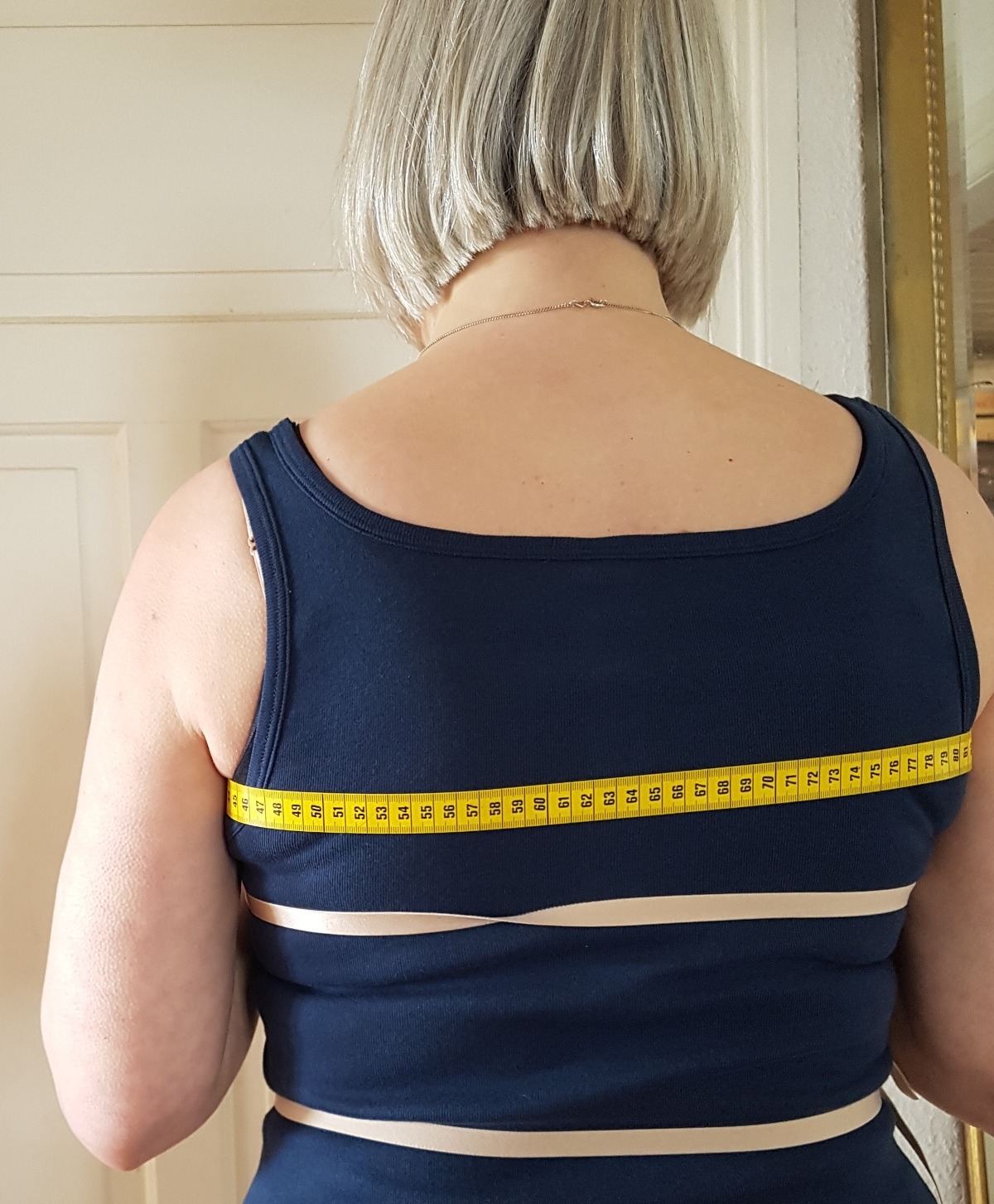 Rückenbreite messen Das Maßband verläuft unter den Armen quer über den Rücken